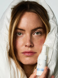 Femme enlacé dans une couette tenant dans ses mains le Spray Sommeil Dodo.