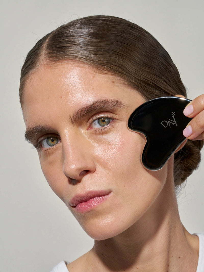 Routine de soins avec le Gua-Sha Day+ en acier inoxydable, pour sculpter le visage et apaiser les tensions musculaires.
