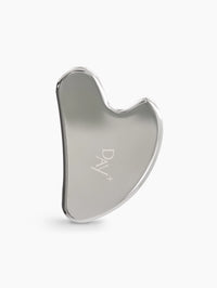 Gua Sha en acier inoxydable avec logo gravé Day+ au centre.