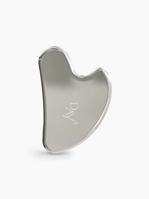 Gua Sha en acier inoxydable avec logo gravé Day+ au centre.