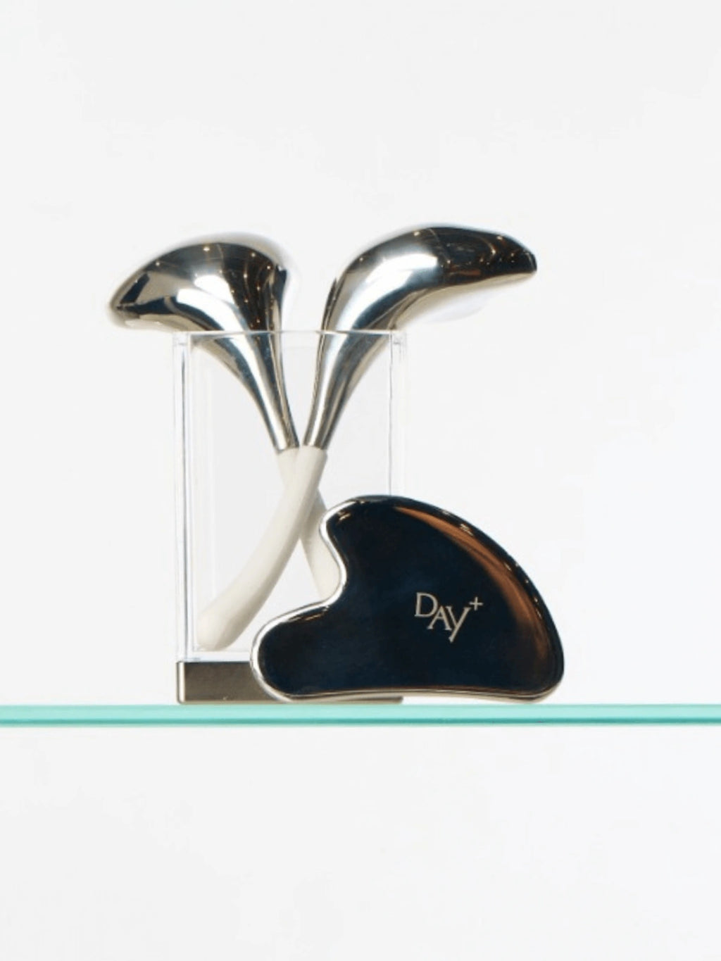 Duo de beauty tools : Cryo-spoons & Gua Sha sur une étagère de salle de bain.