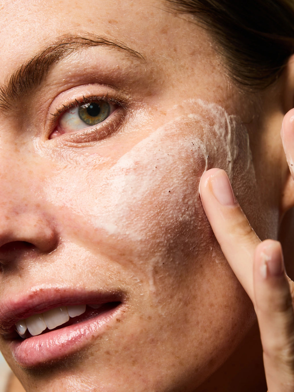 Femme effectuant des mouvements circulaire sur son visage avec le Masque Réparateur & Gommage afin d'exfolier sa peau en douceur.