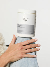 Une Poudre Collagène & Vitamines+ en édition Silver posée sur le genou d'une personne.