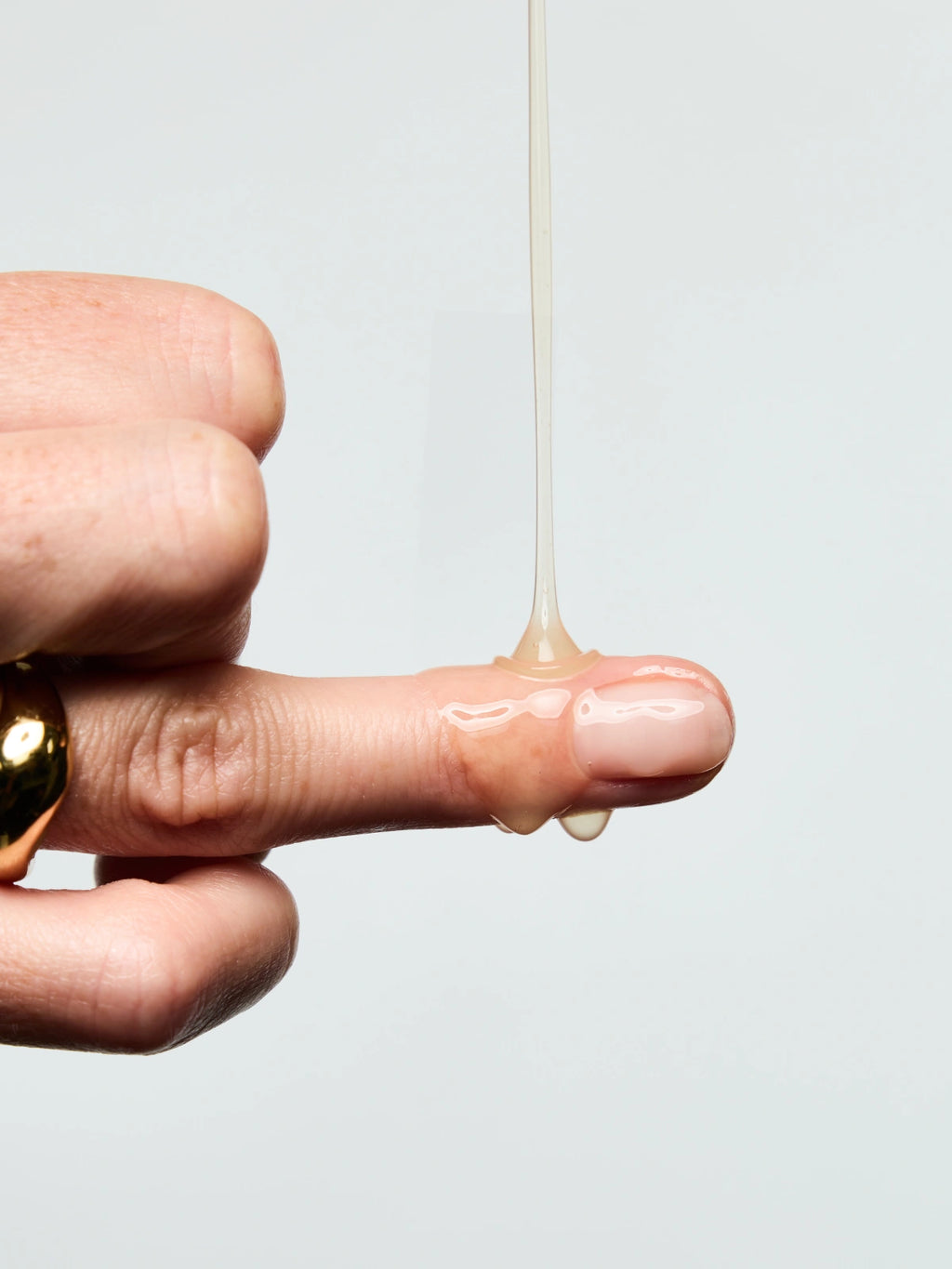 Texture du Sérum Anti-âge Lift Expert coulant sur le doigt d'une femme.