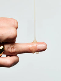 Texture du Sérum Anti-âge Lift Expert coulant sur le doigt d'une femme.