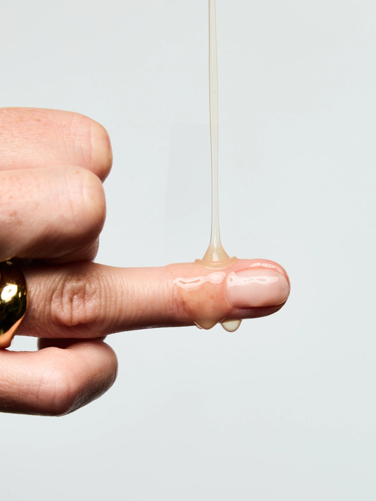 Texture du Sérum Anti-âge Lift Expert coulant sur le doigt d'une femme.