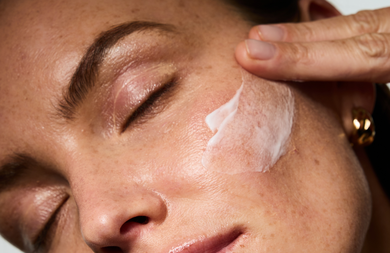 Femme s'appliquant sur la joue, le Sérum Anti-imperfections Correcteur Ultime.