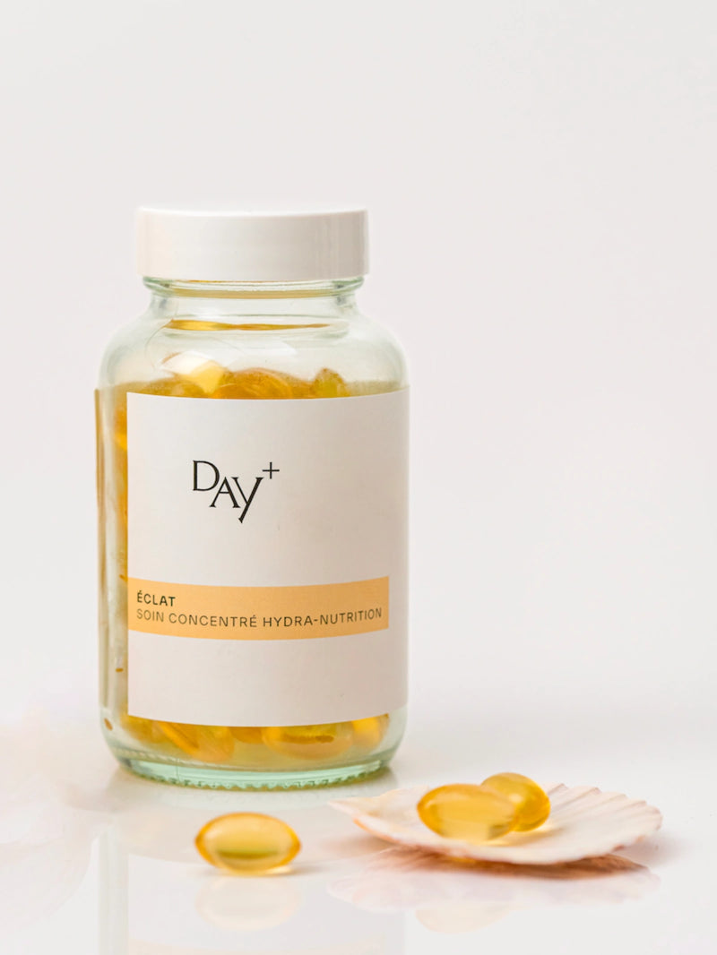 Le Soin Concentré Hydra-Nutrition avec quelques capsules dans un coquillage à côté du pilulier.