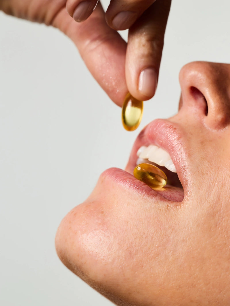 Femme prenant 2 capsules du Soin Concentré Hydra-Nutrition.