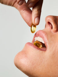 Femme prenant 2 capsules du Soin Concentré Hydra-Nutrition.