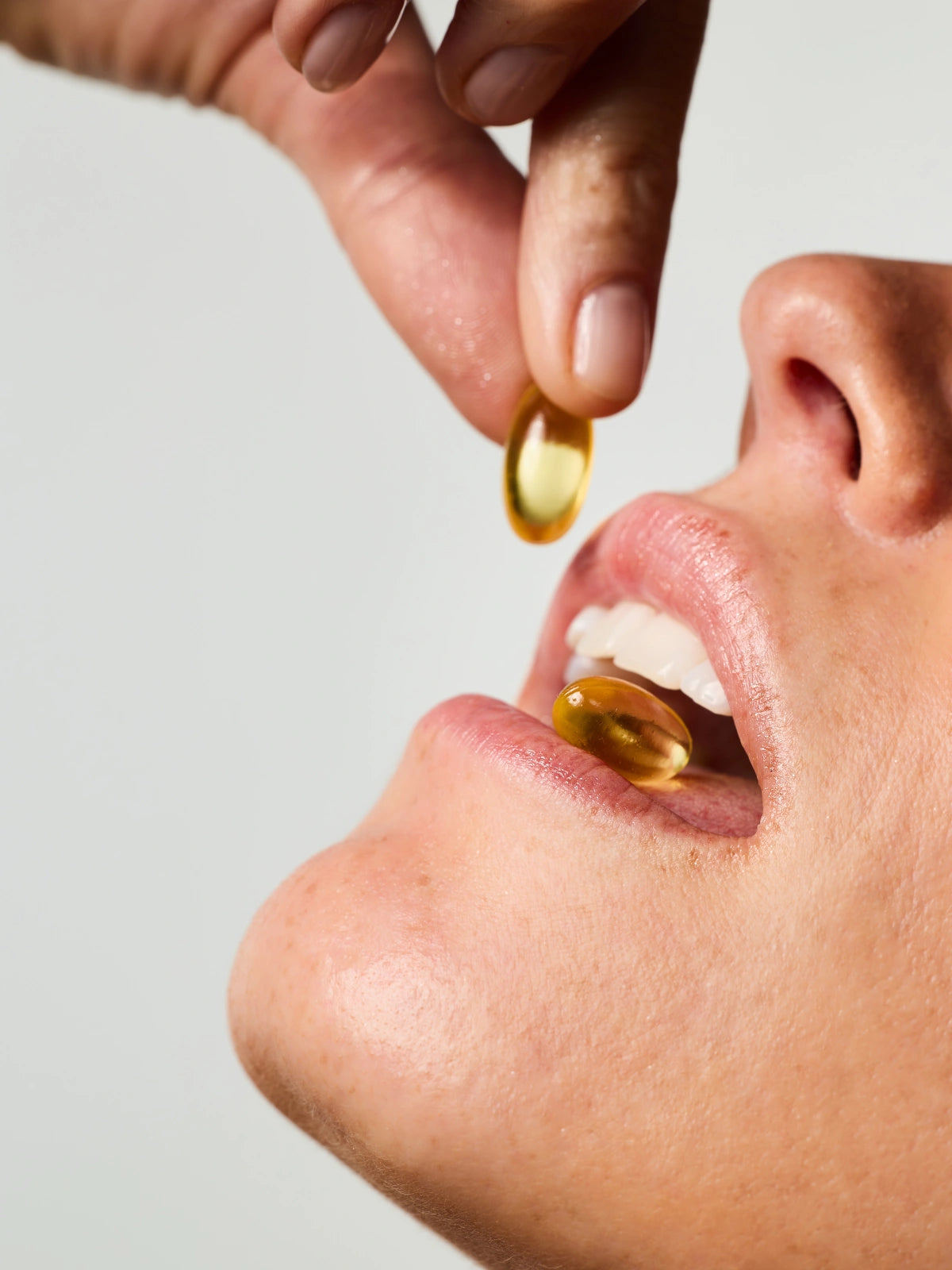 Femme prenant 2 capsules du Soin Concentré Hydra-Nutrition.