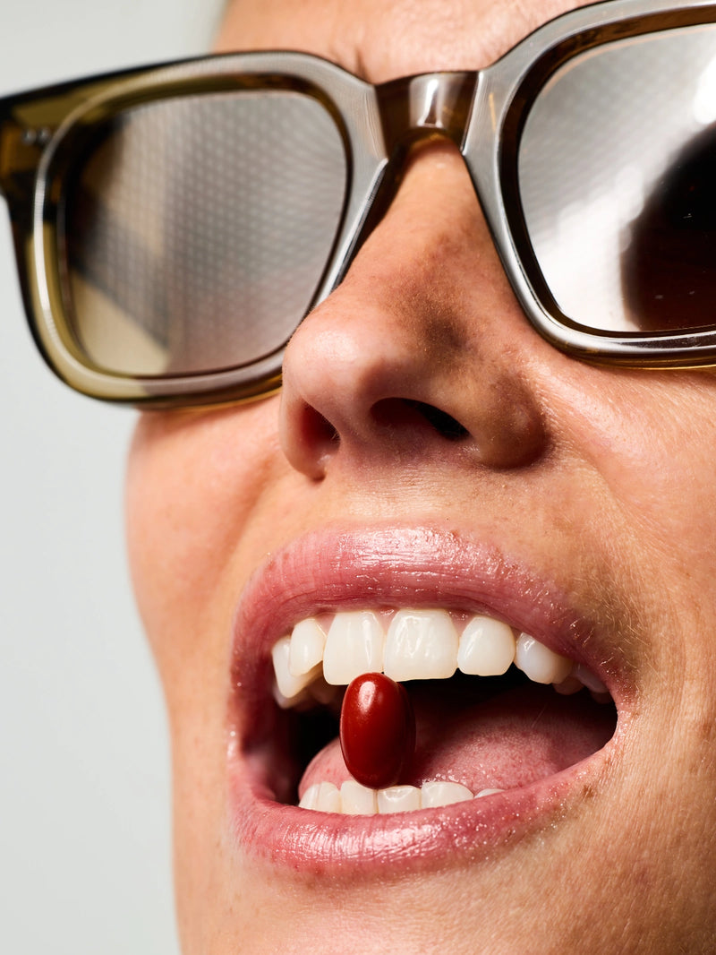 Femme tenant entre ses dents une gélule de Soin Préparateur Essentiel.