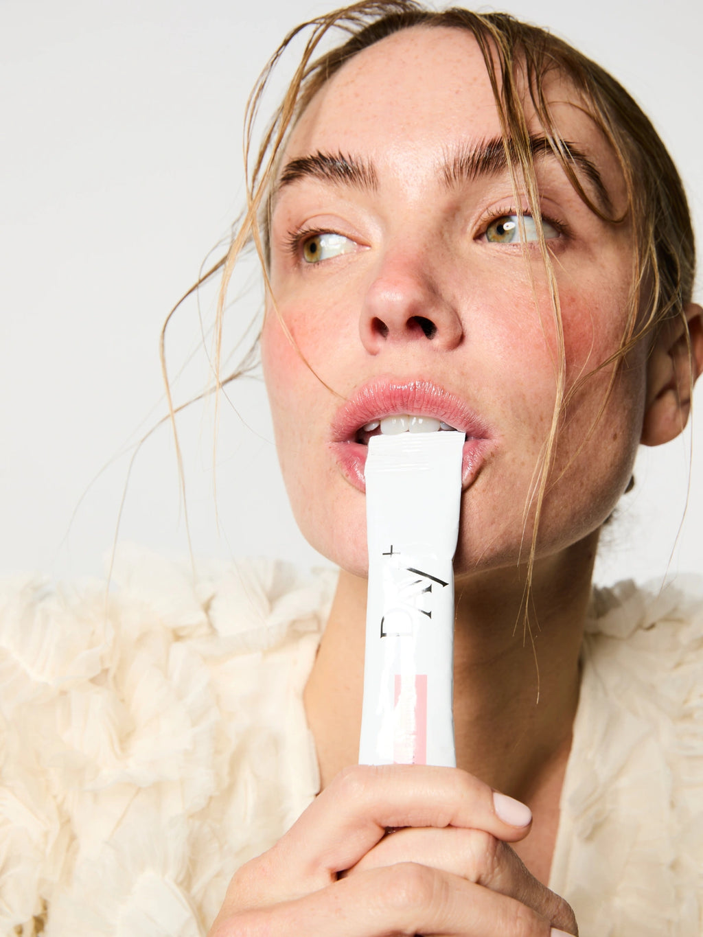 Femme buvant un stick au Collagène marin, Spiruline bio, Acide Hyaluronique, Zinc et Grenade bio.