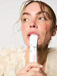 Femme buvant un stick au Collagène marin, Spiruline bio, Acide Hyaluronique, Zinc et Grenade bio.