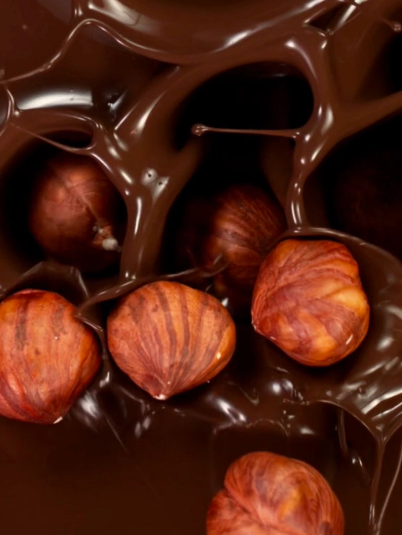 Noisettes tombants dans du chocolat fondu.