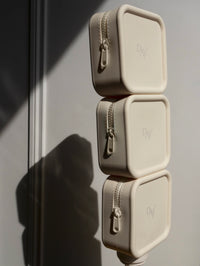 Photo de 3 trousses beige de voyage Day+ empilées les unes sur les autres.