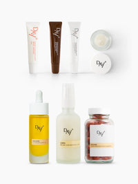 Présentation packshot des produits présents dans le coffret "Essentiels de l'été", composé : d'un Sérum Lèvres Repulpant (Teinte au choix), d'un Eyes & Cheeks Gloss, d'un sérum solaire UV Drops SPF 50, d'une Brume Sublimatrice 3-en-1 et d'un complément Préparateur Solaire.