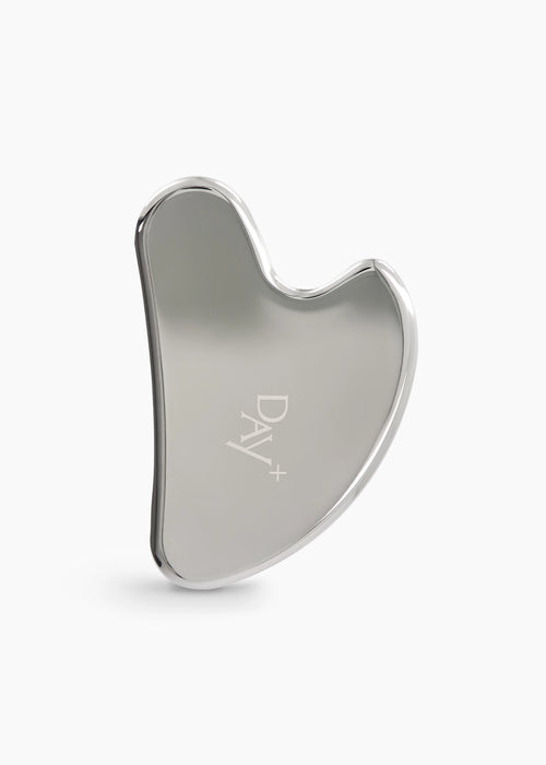 Gua Sha en acier inoxydable avec logo gravé Day+ au centre.