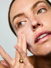 Femme se gommant le visage avec le Masque Exfoliant Perfecteur après l'avoir laissé posé 15 minutes sur le visage.
