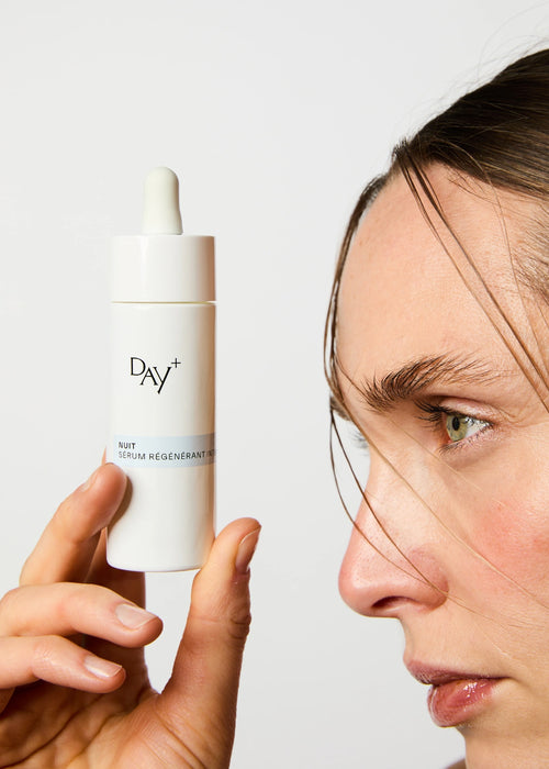 Femme de profil tenant le Sérum Nuit Régénérant Intense face à elle.