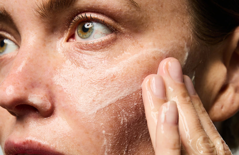 Femme s'exfoliant le visage avec le Masque Réparateur & Gommage.
