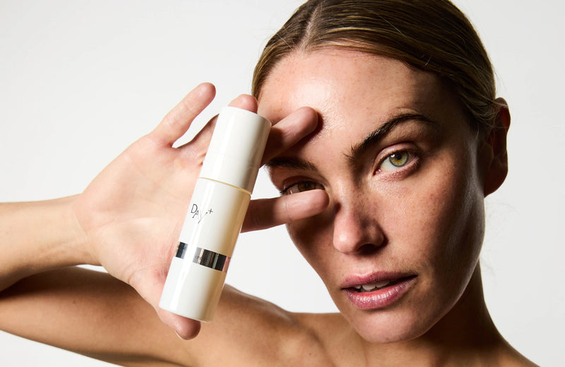 Femme tenant le Sérum Anti-âge Lift Expert proche de son visage.