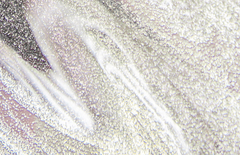 Zoom sur la texture et les reflets des nacres présents dans le Sérum Lèvres Repulpant en teinte 03. Glitter all over.