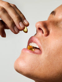 Femme prenant 2 capsules de Soin Concentré Hydra-Nutrition.