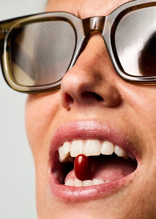 Femme tenant entre ses dents une gélule de Soin Préparateur Essentiel.