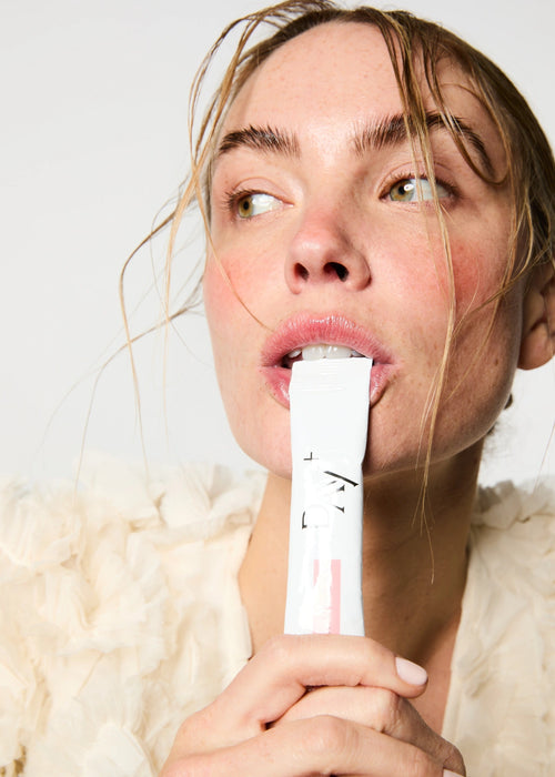 Femme buvant un stick au Collagène marin, Spiruline bio, Acide Hyaluronique, Zinc et Grenade bio.