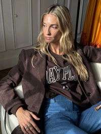 Femme assise sur un fauteuil portant le Sweatshirt Day+ University marron.
