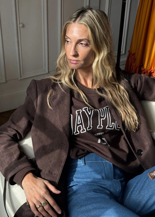 Femme assise sur un fauteuil portant le Sweatshirt Day+ University marron.
