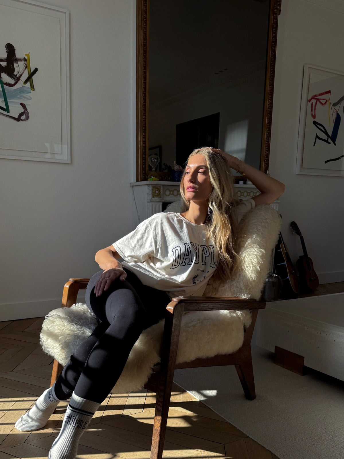 Femme assise dans un fauteuil portant le T-shirt beige de la collection capsule Day+ University.