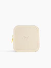 Trousse de voyage Day+ beige avec une fermeture jaune pastel.