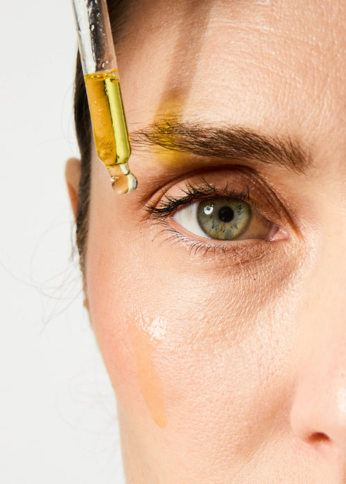 Pipette des UV Drops SPF 50 sur le visage d'une femme.