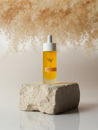 Flacon du sérum solaire UV Drops SPF 50 mis en évidence sur une pierre.