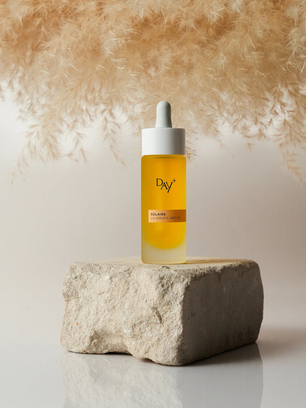Les UV Drops SPF 50 posé sur une pierre.